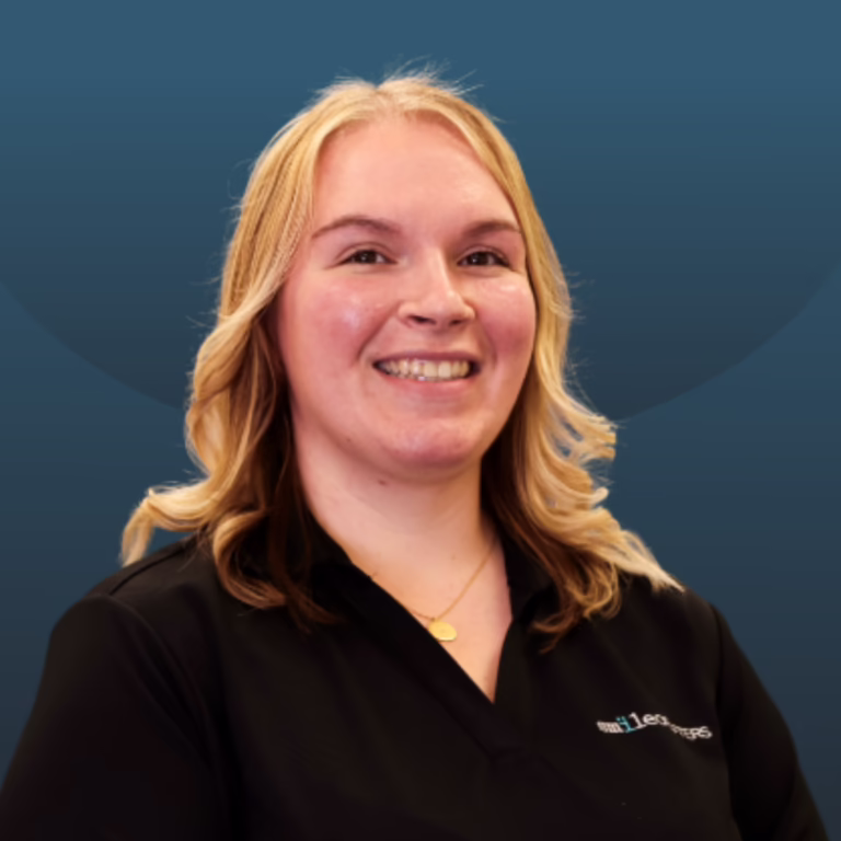 Smiling woman with blonde hair wearing a black polo shirt, posing against a blue gradient background.