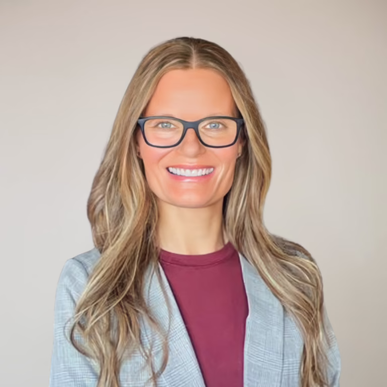 Smiling woman with long wavy blonde hair and black-framed glasses, wearing a light gray blazer over a maroon top, neutral background (professional headshot).