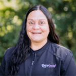 Portrait of a woman smiling outdoors in a black Thorp Dental Center jacket.