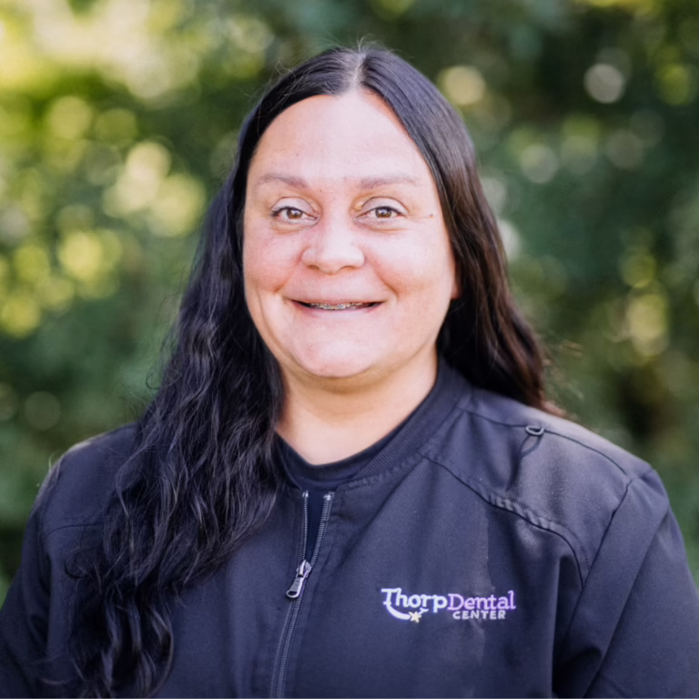 Portrait of a woman smiling outdoors in a black Thorp Dental Center jacket.