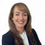 Professional headshot of a smiling woman with light brown hair in a navy blazer and white blouse, against a plain white background