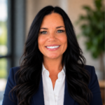 Professional headshot: smiling woman with long dark hair, wearing a navy blazer and white shirt in an office setting.