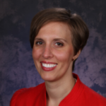Professional headshot of a smiling woman with short brown hair wearing a red blouse.
