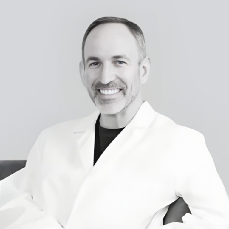 Smiling male doctor in a white lab coat, facing the camera.