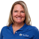 Smiling woman in a blue polo shirt with a dental care logo on the left chest, against a white background, portrait.