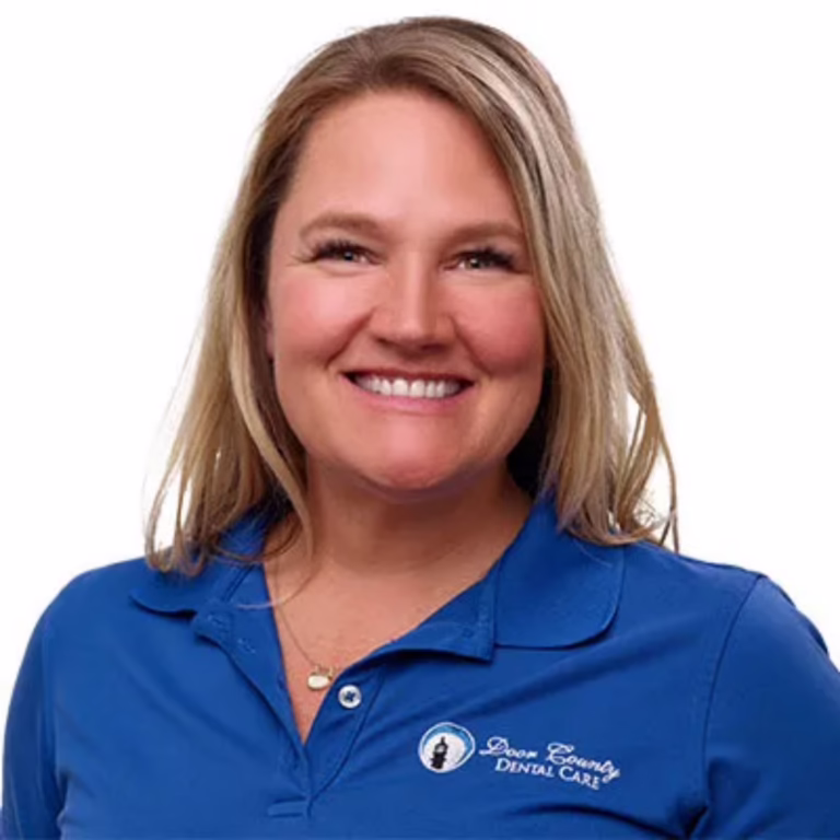 Smiling woman in a blue polo shirt with a dental care logo on the left chest, against a white background, portrait.