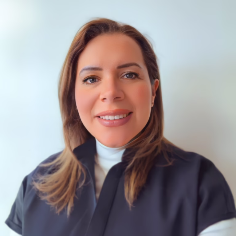 Portrait of a smiling woman with shoulder‑length light brown hair, wearing a black top over a white turtleneck, against a pale blue background.