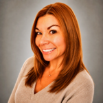 Portrait of a smiling woman with shoulder-length auburn hair in a beige sweater.