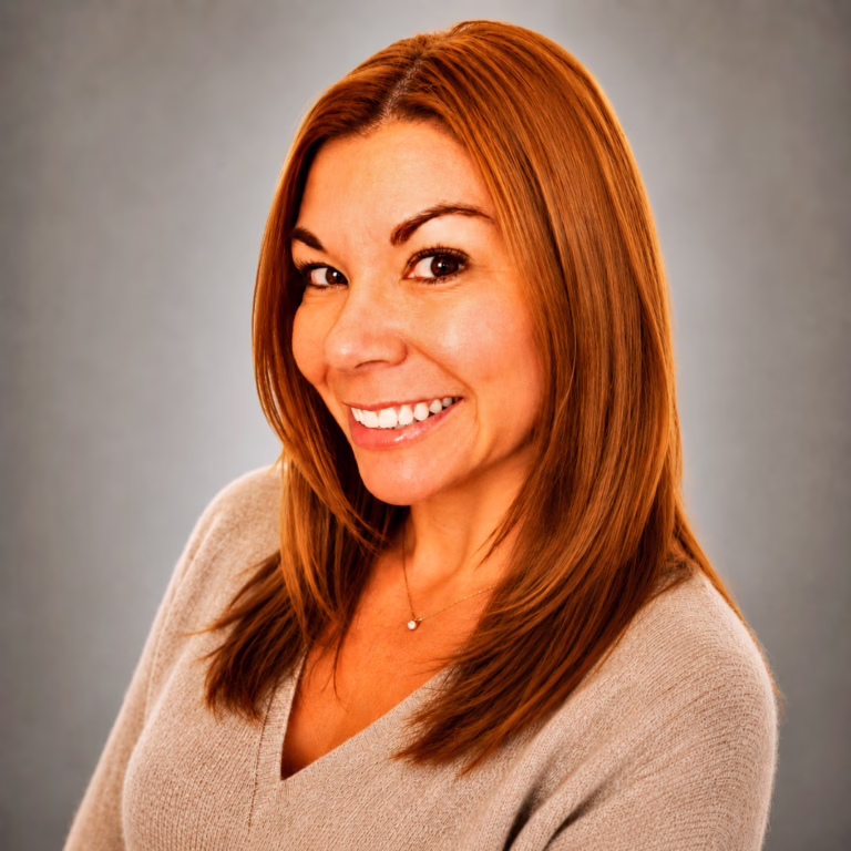 Portrait of a smiling woman with shoulder-length auburn hair in a beige sweater.